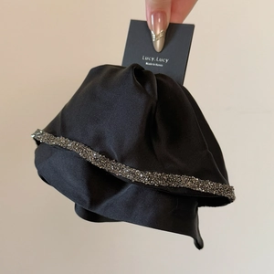 Detail of black satin ribbon hair clip with hand-set grey rhinestones and silk texture