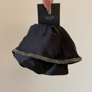 Detail showing the black satin fabric texture and silver rhinestone trim on the hair clip