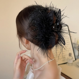 Détail d'une pince à cheveux en plumes noires avec nœud en dentelle et perles