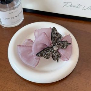 Vue détaillée de la pince à cheveux en organza violet avec papillon noir en strass