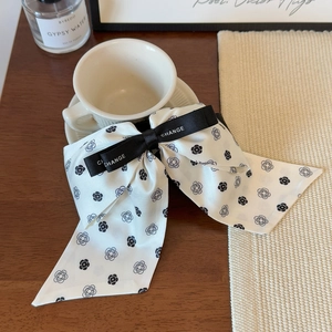Detail of camellia flower pattern on white bow hair clip next to a coffee cup