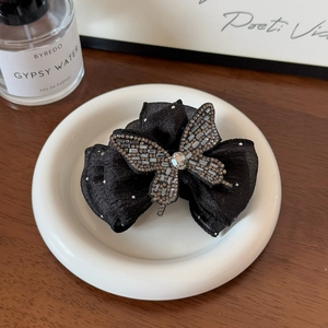 Grande pince à cheveux élégante en tissu noir avec un détail de papillon en strass brillant