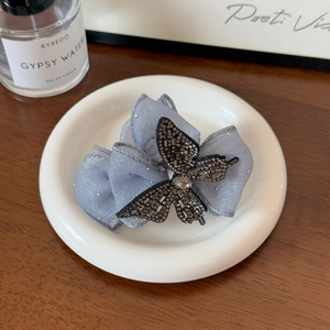 Détail d'une pince à cheveux grise élégante avec nœud papillon en cristal et perles fines
