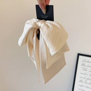 Gros plan sur la pince à cheveux élégante avec un grand nœud crème en tissu texturé