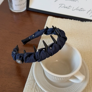 Détail du serre-tête bleu marine à pois avec dents antidérapantes et breloque papillon
