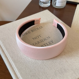 Detail of light pink satin headband featuring wide design and soft glossy texture