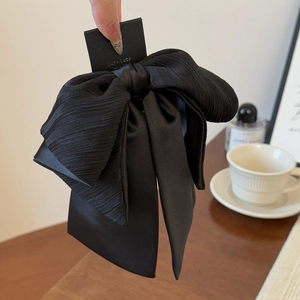Détail d'une pince à cheveux à double nœud noir avec tissu texturé et finition satinée