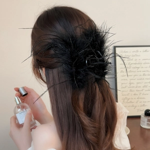 Detail view of a large black ostrich feather hair claw clip for elegant updo hairstyles
