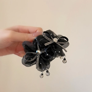 Detailed close-up of mesh flower hair claw clip with rhinestones and beaded tassel