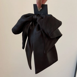 Détail de la pince à cheveux nœud noir élégant avec textures en tissu et ruban satin