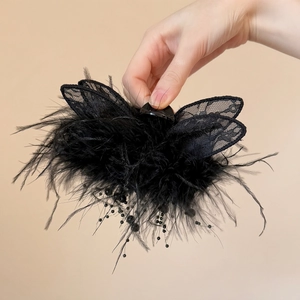 Détail d'une pince à cheveux avec plumes noires, dentelle et franges perlées élégantes