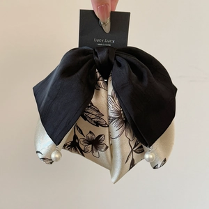 Détail d'une barrette noeud noir et blanc avec imprimé floral et perles fantaisie