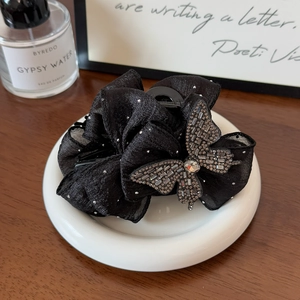 Détail d'une pince à cheveux nœud noir élégante avec strass sur fond en bois