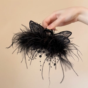 Détail de la pince à cheveux en plumes noires avec papillon en dentelle et glands
