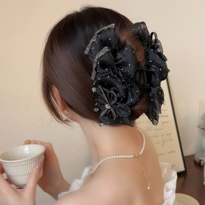 Macro detail of the elegant black satin bow hair claw clip with sparkling rhinestones and lace