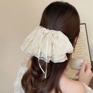 Elegant off-white pleated organza hair clip with pearls and ribbon bow on model hair