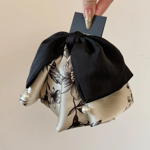 Détail d'une pince à cheveux avec nœud en satin noir, imprimé à l'encre et perles