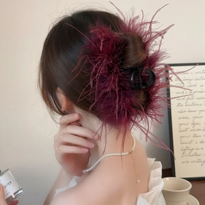 Detail of burgundy ostrich feather hair claw clip used in an elegant French bun hairstyle