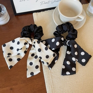 Close-up of black and white polka dot satin hair scrunchies with long ribbon streamers