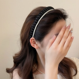 Close-up of a padded black headband with white polka dots and pearl bead embellishments