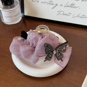 Détail d'une élégante pince à cheveux papillon en tulle mauve avec des strass étincelants