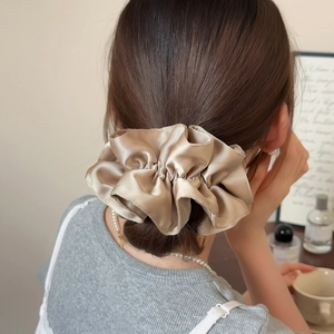 Detail of champagne satin scrunchie styled in a voluminous bun hair wrap for women