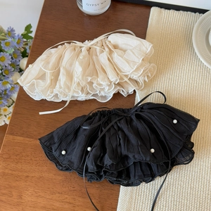 Detail of pleated hair clips with pearls and ribbons in cream and black tones