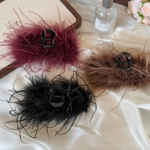 Detailed view of hair claws with lush ostrich feathers in wine red, brown, and black