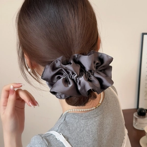 Charcoal grey large satin scrunchie with pleated texture shown on a low hair bun