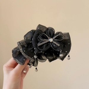 Detailed macro of black organza bow hair claw clip with rhinestones and bead tassels