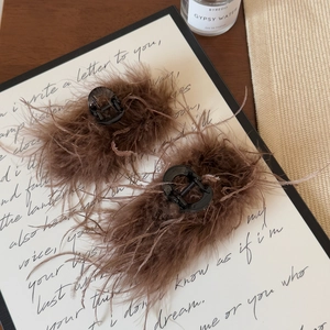 Detailed shot of premium brown ostrich feather hair claw clip on an elegant display card