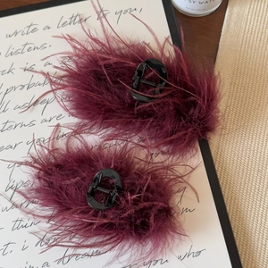Detail showing elegant burgundy ostrich feather hair claw clips with fluffy textures