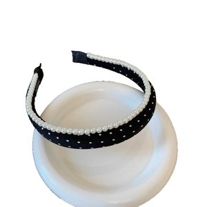 Black and white polka dot headband with faux pearl trim on an elegant white base