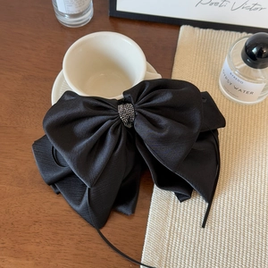 Detail of a large black satin bow hair clip with sparkling silver rhinestone center
