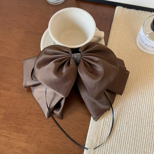 Detailed view of the brown satin bow hair clip with sparkling crystal center on a desk