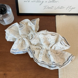 Detailed view of layered lace scrunchies with blue and black stripe edges on wood