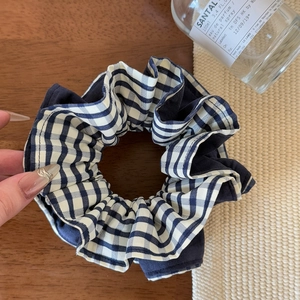 Navy blue and blue-white gingham double-layered fabric scrunchie on a textured fabric