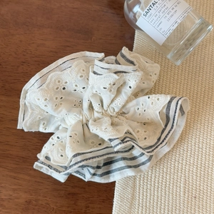 Detailed shot of white lace and striped scrunchie on an elegant wooden tabletop