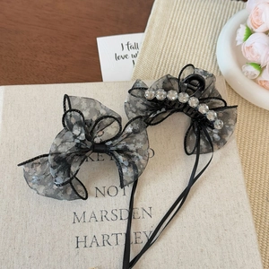 Floral mesh bow hair claw clips with rhinestones and ribbon tassels on a vintage book
