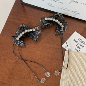 Detail of floral black tulle hair clips with crystal accents and long ribbon tassels