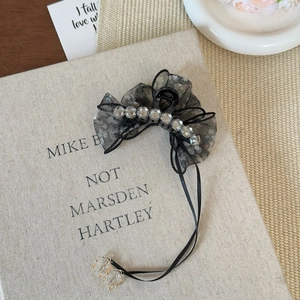 Detail of black mesh bow hair claw with sparkling rhinestones and long ribbon tassels