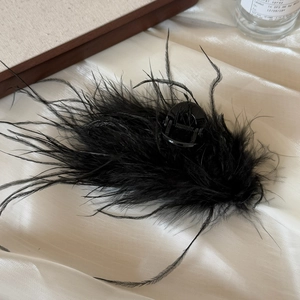 Detail showing elegant black ostrich feathers on a glossy hair claw clip for women