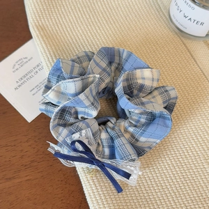 Detailaufnahme von blau-weißem Karo-Haargummi mit Spitzenrand und Satin-Schleife