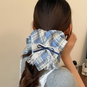 Dettaglio di elastico per capelli a quadretti blu con pizzo bianco e fiocco