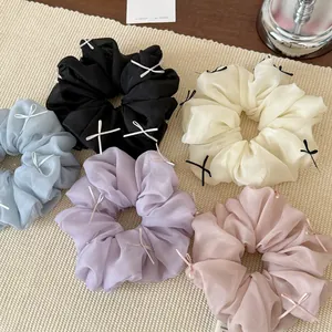 Detail of five organza scrunchies with delicate ribbon bows in pastel colors and black