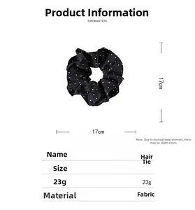 Detailed view of a black fabric scrunchie with white heart patterns and 17cm diameter size