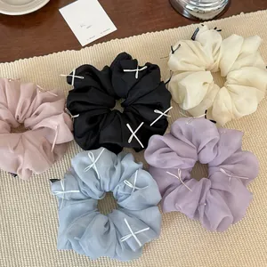Close-up of fluffy chiffon scrunchies with delicate ribbons in five assorted soft colors
