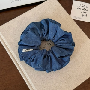 Detail of dark blue denim scrunchie with soft fabric texture and decorative white label