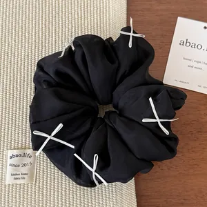 Detailed texture of black fluffy scrunchie with white bows and elegant silk fabric