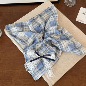 Dettaglio di scrunchie a quadri blu con pizzo e fiocco su un libro d'epoca